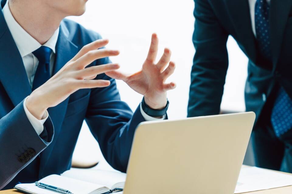 スーツを着た二人のビジネスパーソンが互いに話し合っている様子。